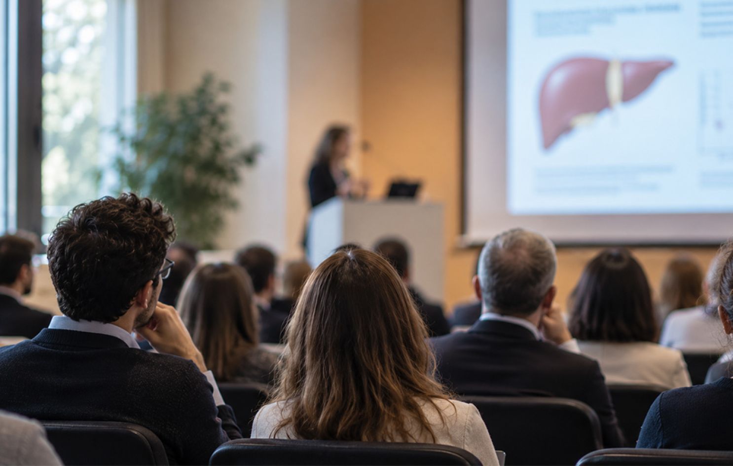 Conferenza scientifica sui disturbi alcol-correlati con professionista che presenta una slide dedicata al fegato